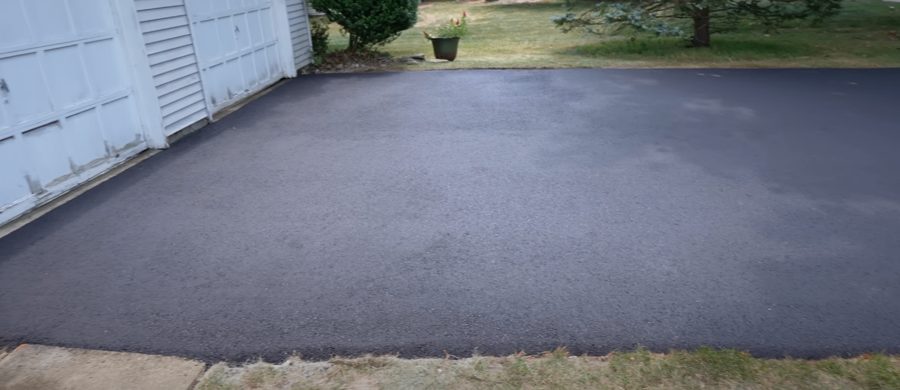 scaled and sunken driveway section beside a downspout before removal